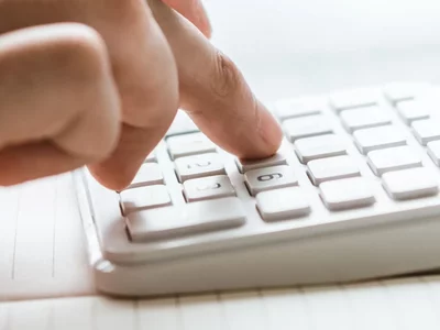 Taschenrechner auf einem Schreibtisch Jemand bedient einen auf dem Schreibtisch liegenden Taschenrechner