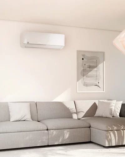 Helles Wohnzimmer mit grauem Ecksofa und einem weißen Remko Klimagerät an der Wand